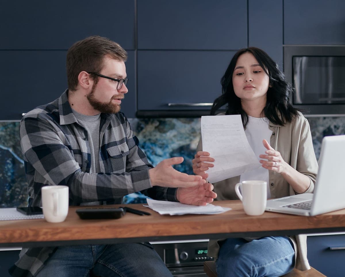 A person reviewing home costs on a laptop at a kitchen table