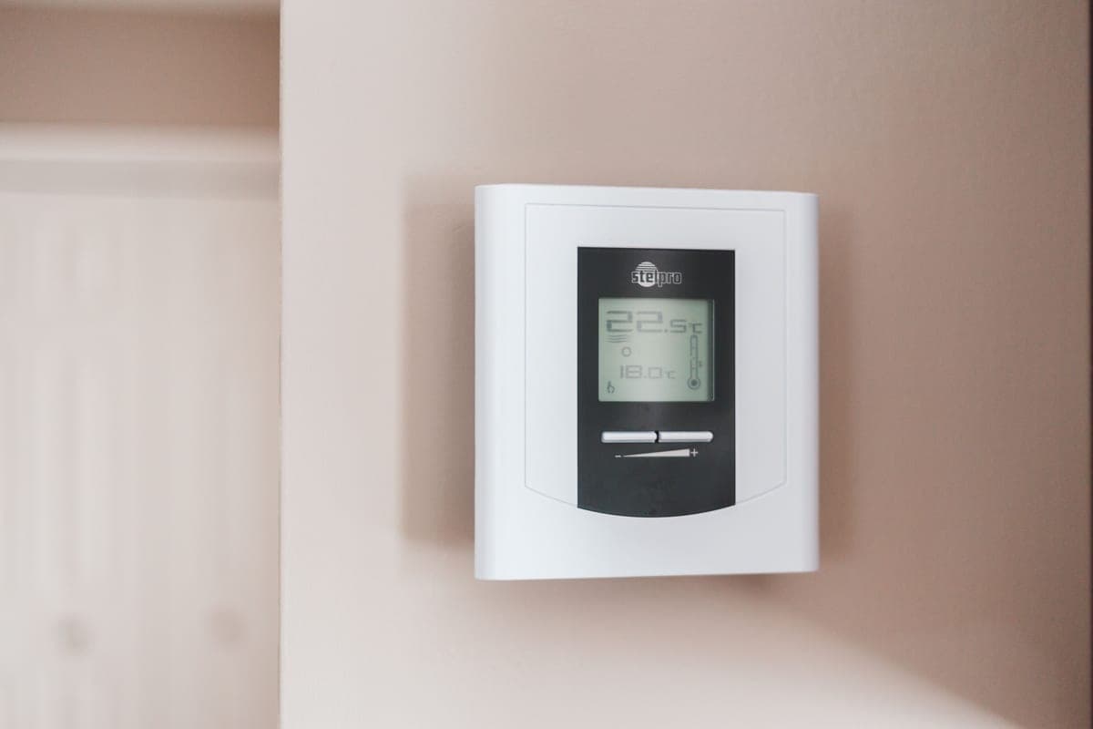 A round smart thermostat mounted on a wall showing the temperature